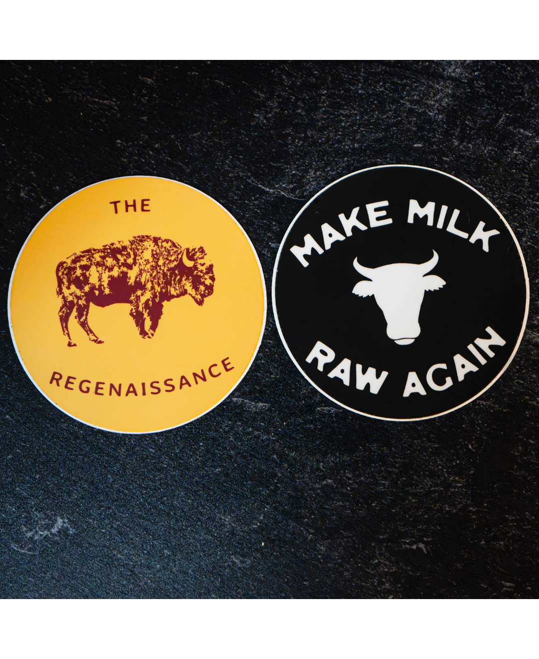 The Regenaissance Sticker Pack by Sticker Mule features two round vinyl stickers: one yellow with a bison and THE REGENAISSANCE, and one black with a cow head and MAKE MILK RAW AGAIN—great for supporters of real food.