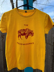 A yellow Kids OG Bison Tee by Farm Fresh Clothing hangs outdoors on a hanger, featuring a maroon bison graphic above THE REGENAISSANCE. Made in the USA from organic cotton, its inspired by regenerative agriculture.