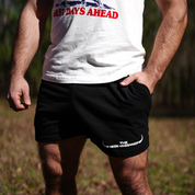 A person stands outdoors in a white BEST DAYS AHEAD T-shirt and Los Angeles Apparel Mens Longhorn Shorts, with THE REGENAISSANCE on them. Blurred greenery in the background hints at regenerative agriculture.