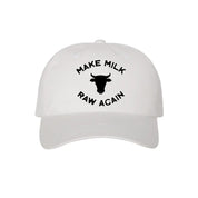 The MMRA Cow Cap by Farm Fresh Clothing is a white hat featuring a black cow head and the slogan "MAKE MILK RAW AGAIN," ideal for raw milk enthusiasts and food freedom supporters.
