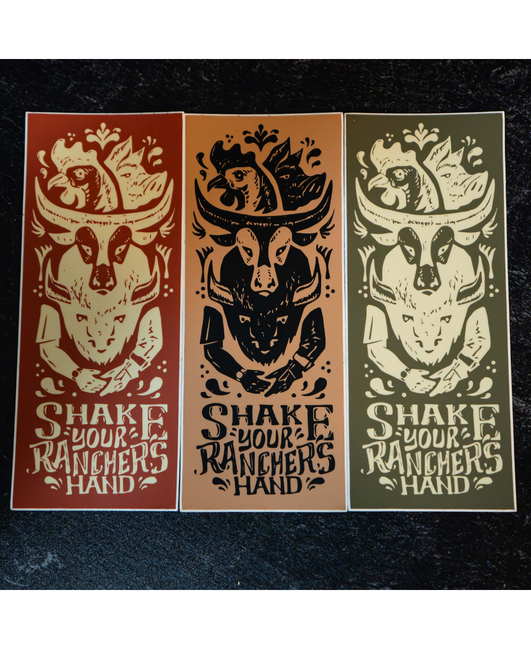 The Regenaissance Sticker Pack from Sticker Mule features three rectangular vinyl stickers with a stylized goat skull above “SHAKE YOUR RANCHER’S HAND.” Each design highlights real food and regenerative agriculture in earthy tones on a dark textured background.