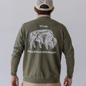 Wearing the Farm Fresh Clothing Bison Crewneck Sweatshirt—green organic cotton with a white bison and THE REGENAISSANCE on the back—and a beige mesh cap, this person stands facing away, embodying sustainable style.