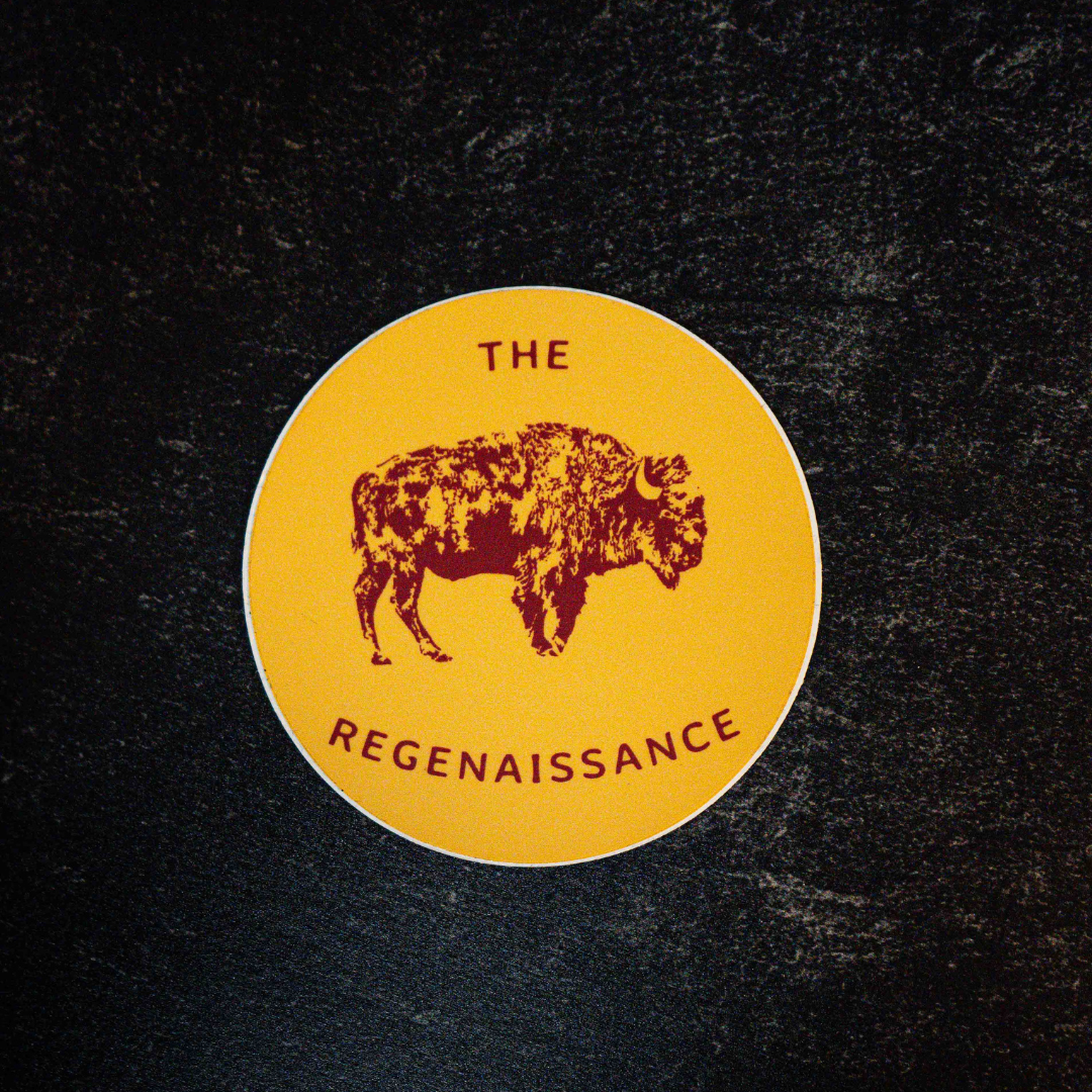 The Regenaissance Sticker by Sticker Mule is a circular yellow vinyl sticker with a maroon Great American Bison illustration and THE REGENAISSANCE in maroon, shown on a dark textured background.