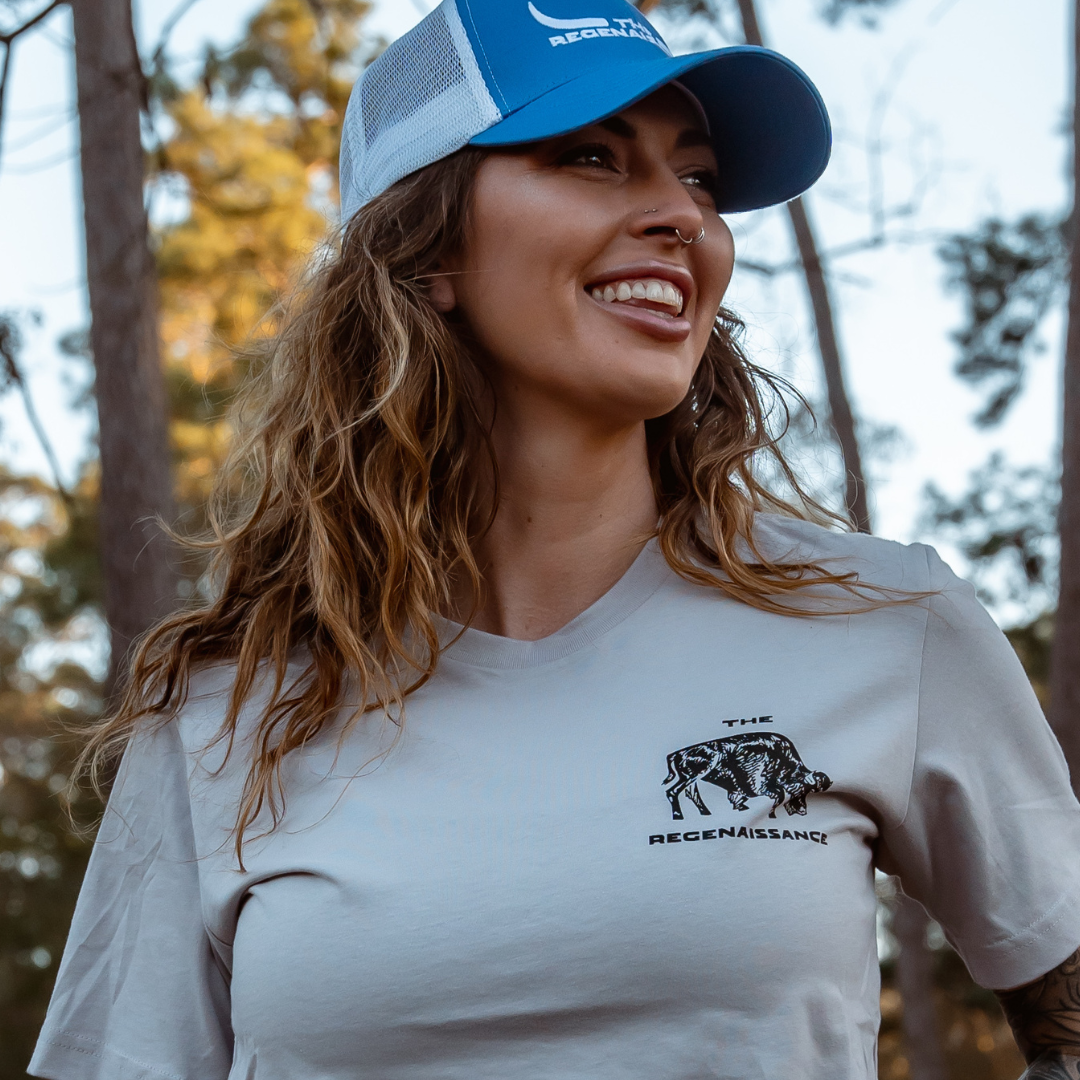 White and a gray T-shirt with “The Regenaissance” bull graphic, celebrating food freedom outdoors among trees and sunlight.