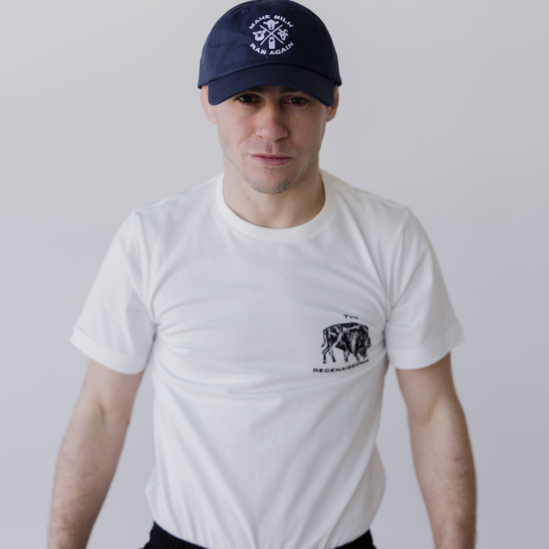 A person wearing the Farm Fresh Clothing MMRA Trinity Cap, a white graphic t-shirt, and black pants stands facing the camera with a neutral expression against a plain light background.