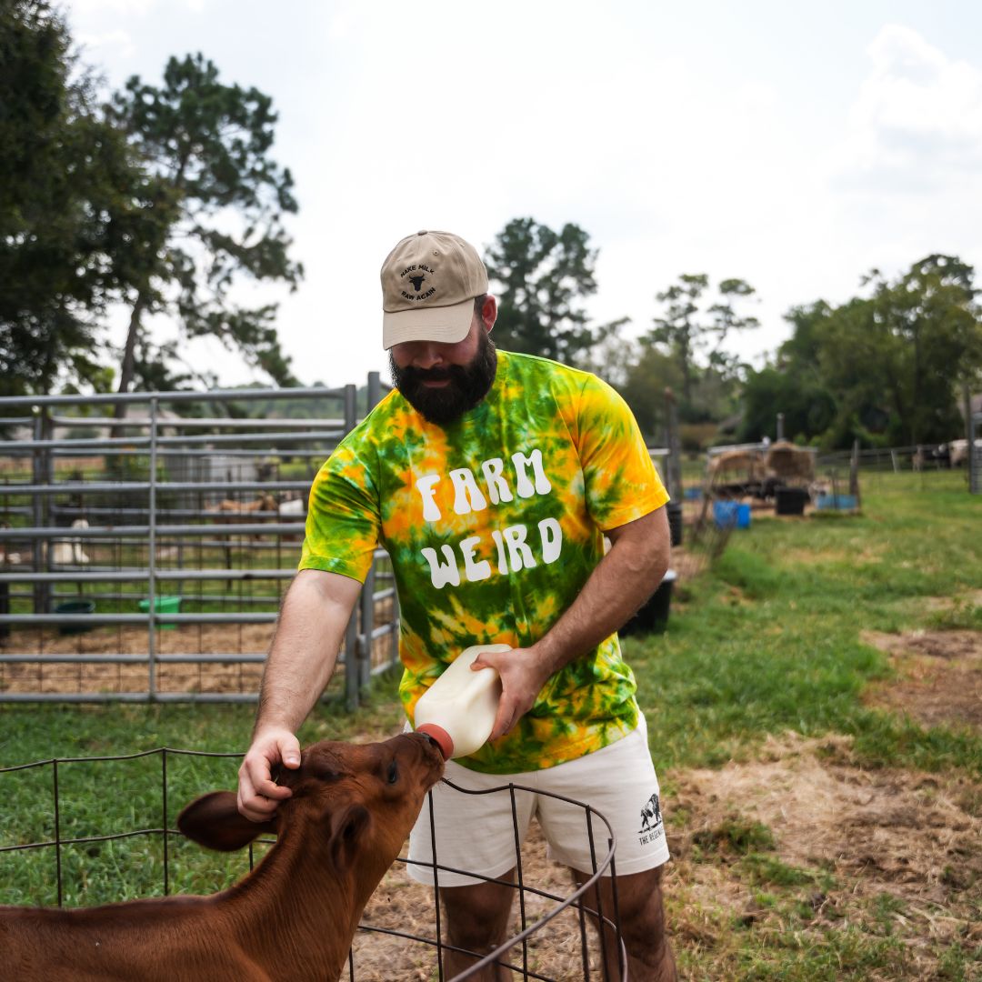Male model wearing crème Regen Men’s Shorts, front view emphasizing relaxed fit and breathable cotton blend while feeding calf.