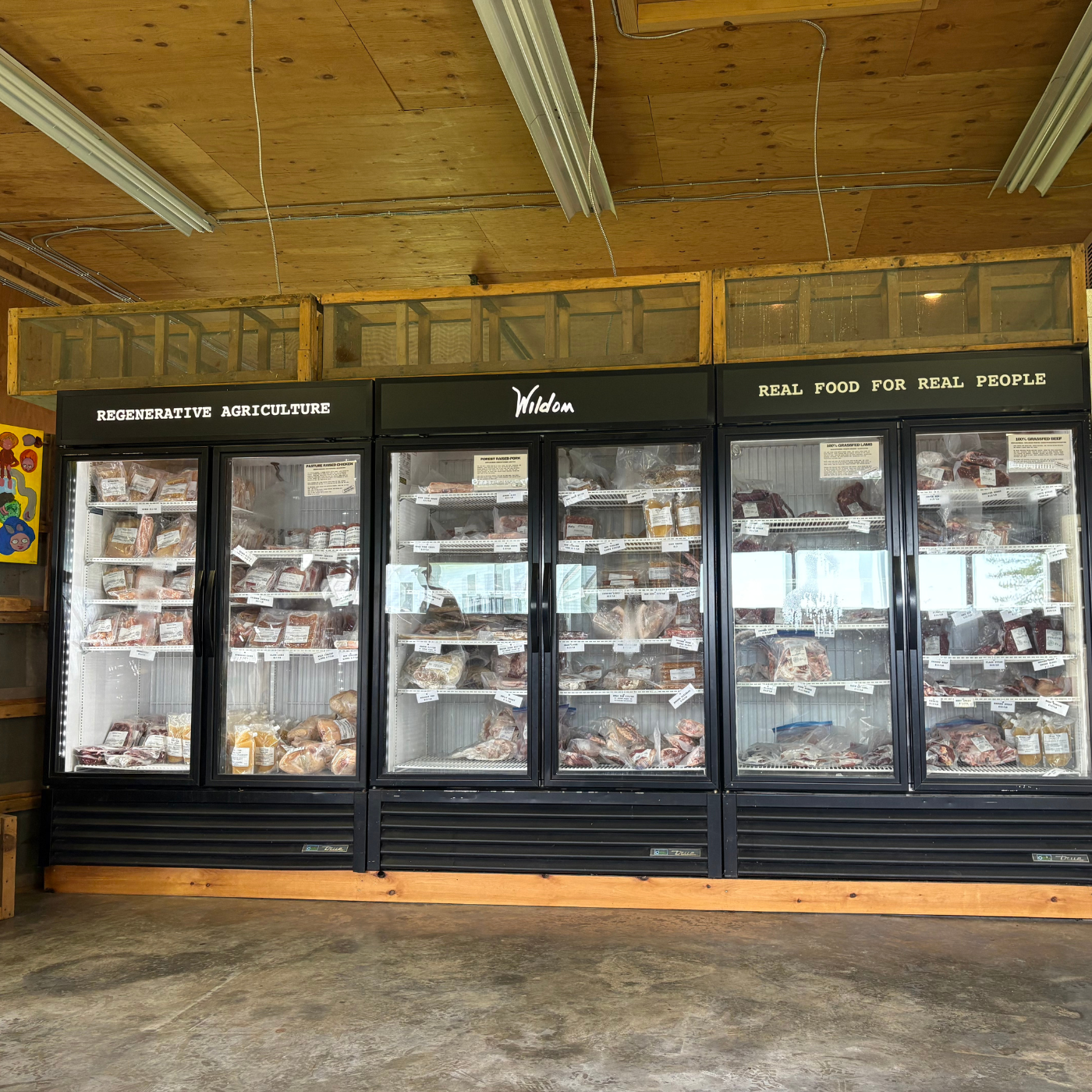 Three refrigerated display cases with food products inside, branded &#39;Wildom&#39;, in a store setting.
