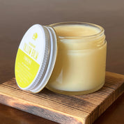 Jar of Frankencense Tallow Balm on a wooden coaster with a blurred background