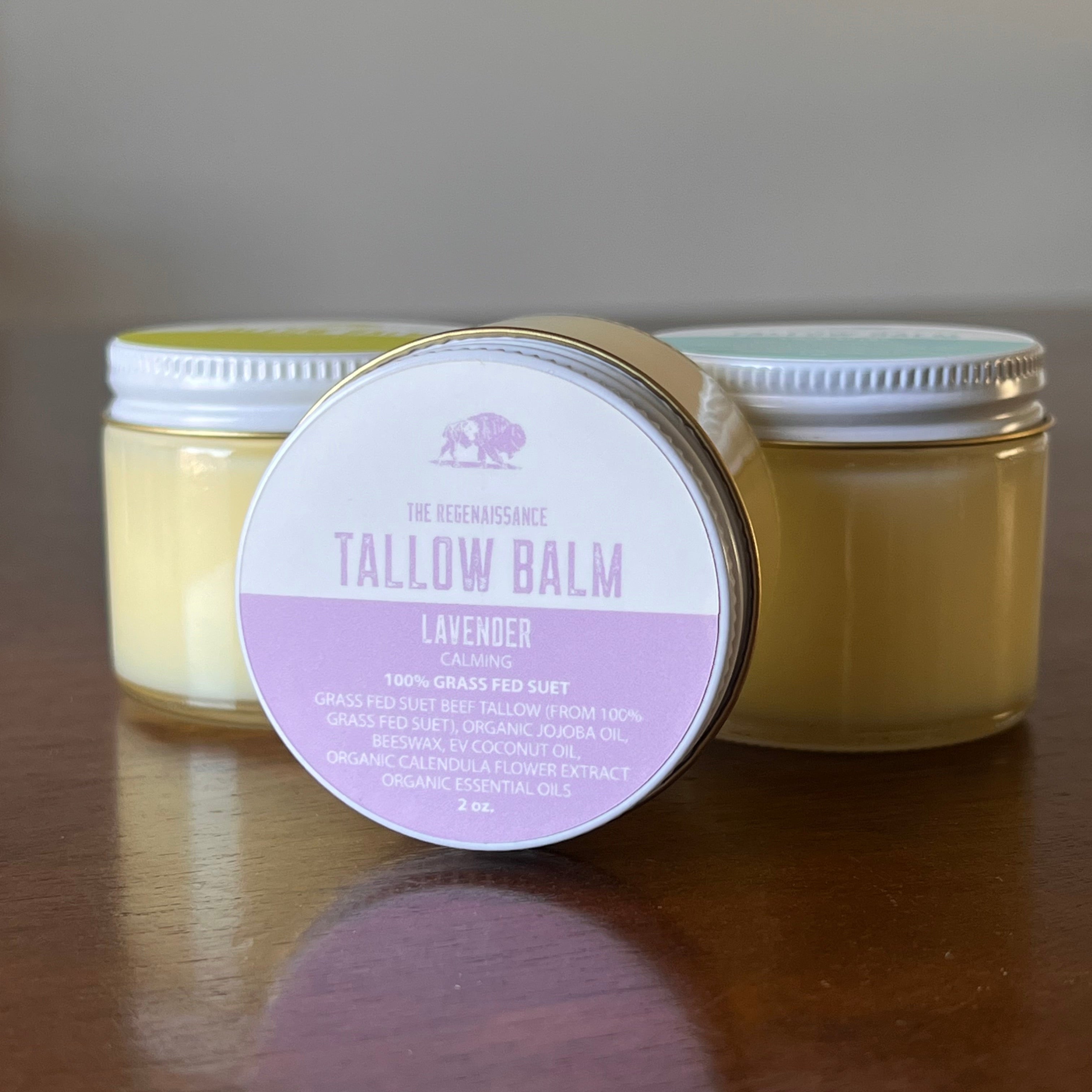 Jar of Lavender Tallow Balm on a wooden shelf in front of two other jars of tallow balm