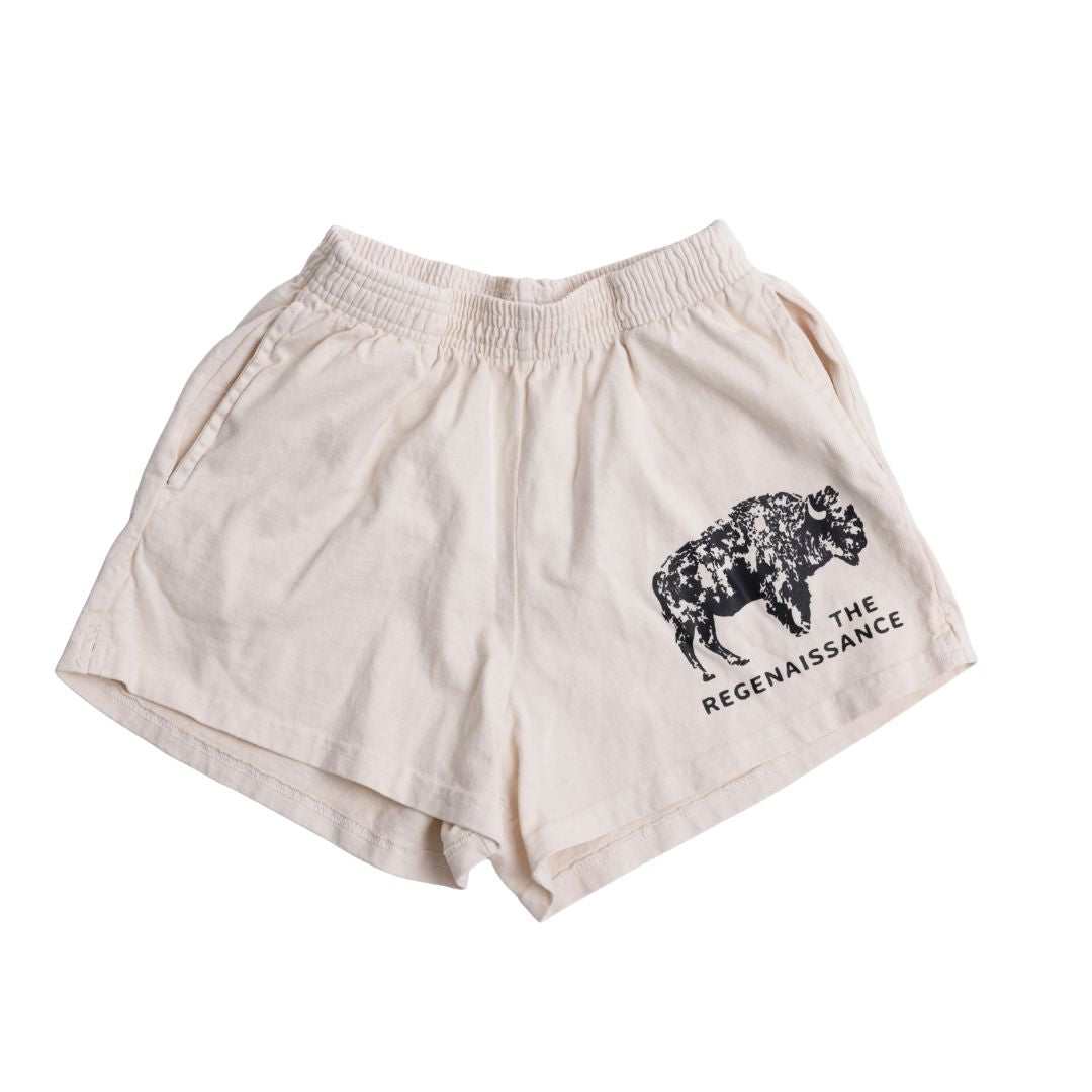 Los Angeles Apparel Women's Bison Shorts in Creme with an elastic waistband, black regenerative agriculture-inspired graphic, and "THE REGENAISSANCE" text on the front left leg.