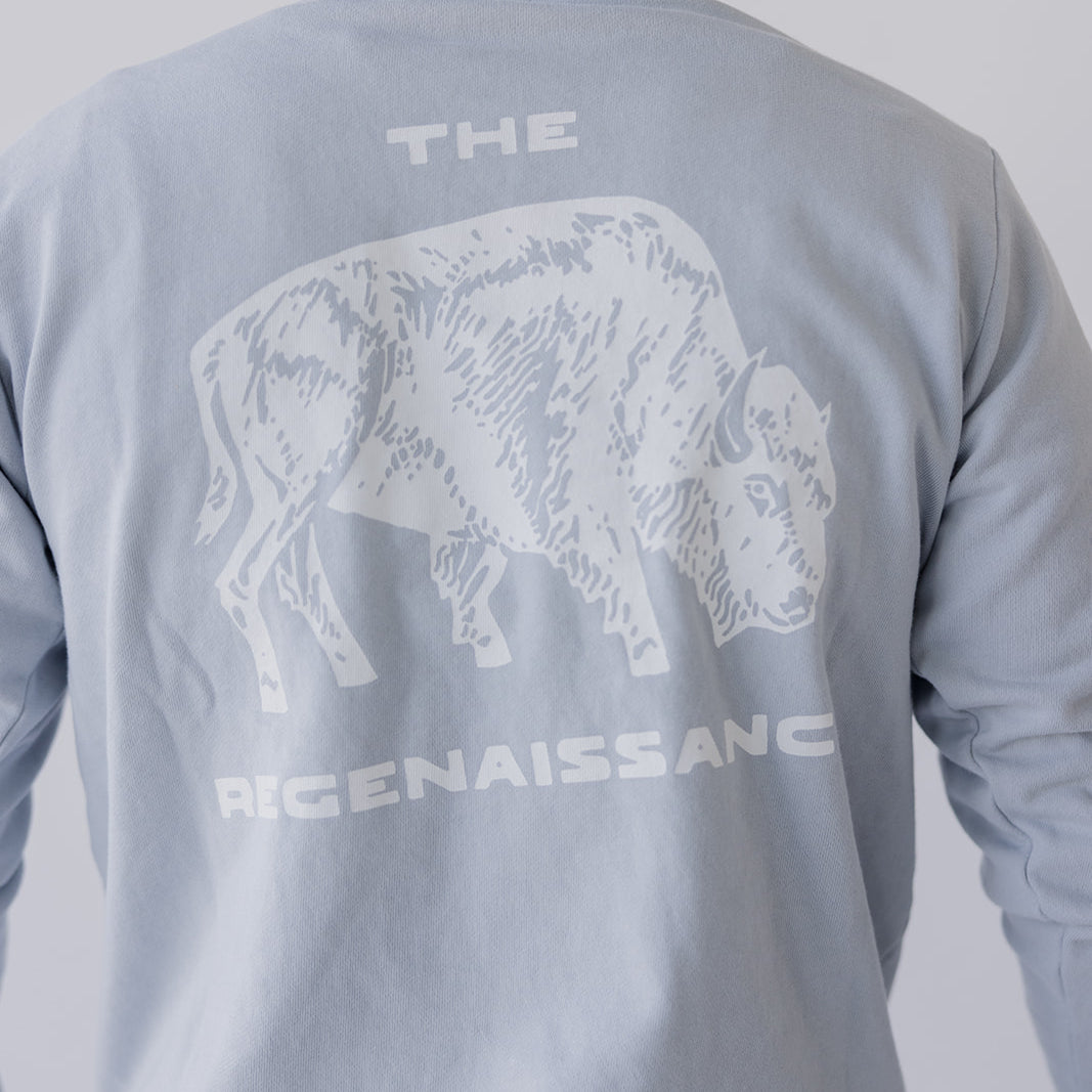 A person, shown from behind, wears the Farm Fresh Clothing Bison Crewneck Sweatshirt in light gray—an organic cotton top featuring a white bison graphic and THE REGENAISSANCE on the back, embodying sustainable values.